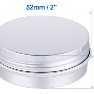 May include: A small, round, silver-colored metal tin with a screw-on lid. The tin measures 2 inches in diameter and 0.8 inches in height. The dimensions are clearly labeled on the image. The container is suitable for storing small items.