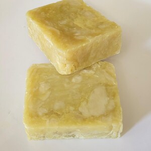 May include: Two rectangular bars of soap with a marbled, translucent yellow-green appearance. The surface of each bar shows a semi-solid texture with lighter, opaque patches embedded within the translucent base, creating a natural, uneven look.