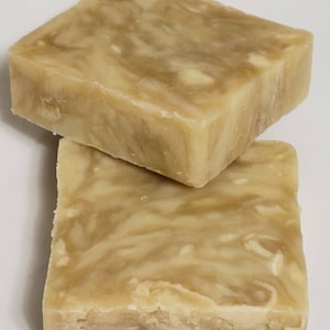 May include: Two bars of handmade soap with a swirl pattern in shades of beige and brown.