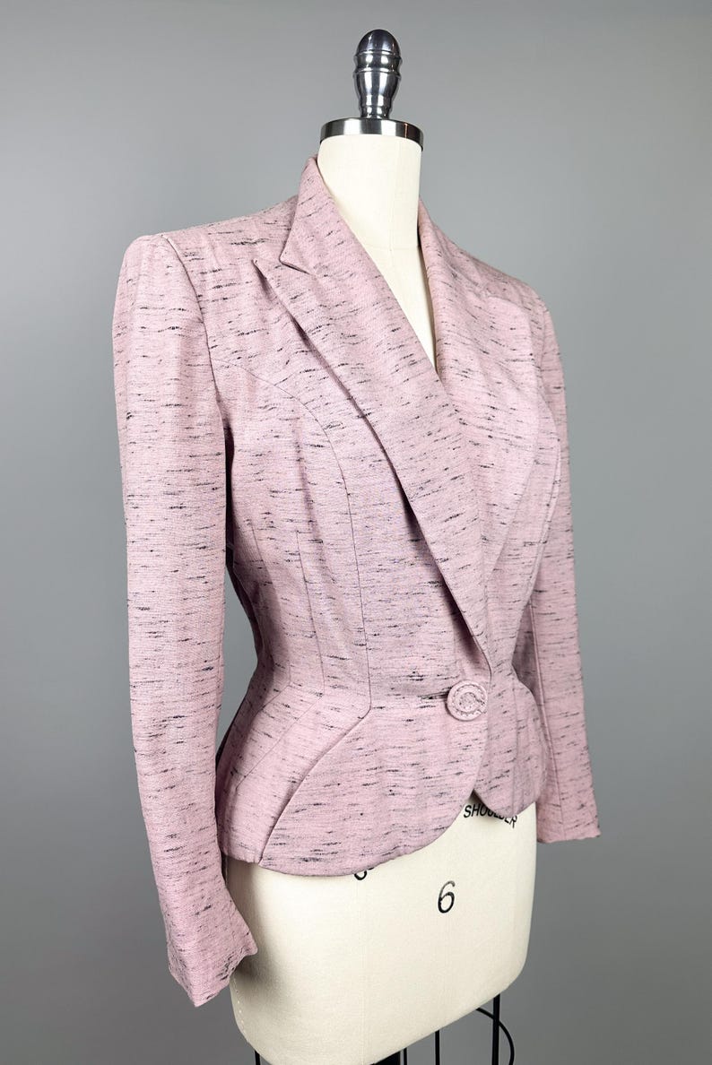 Puede incluir: Una chaqueta rosa con un patr&oacute;n moteado y un cierre de un solo bot&oacute;n. La chaqueta tiene una silueta ajustada y una longitud ligeramente recortada.