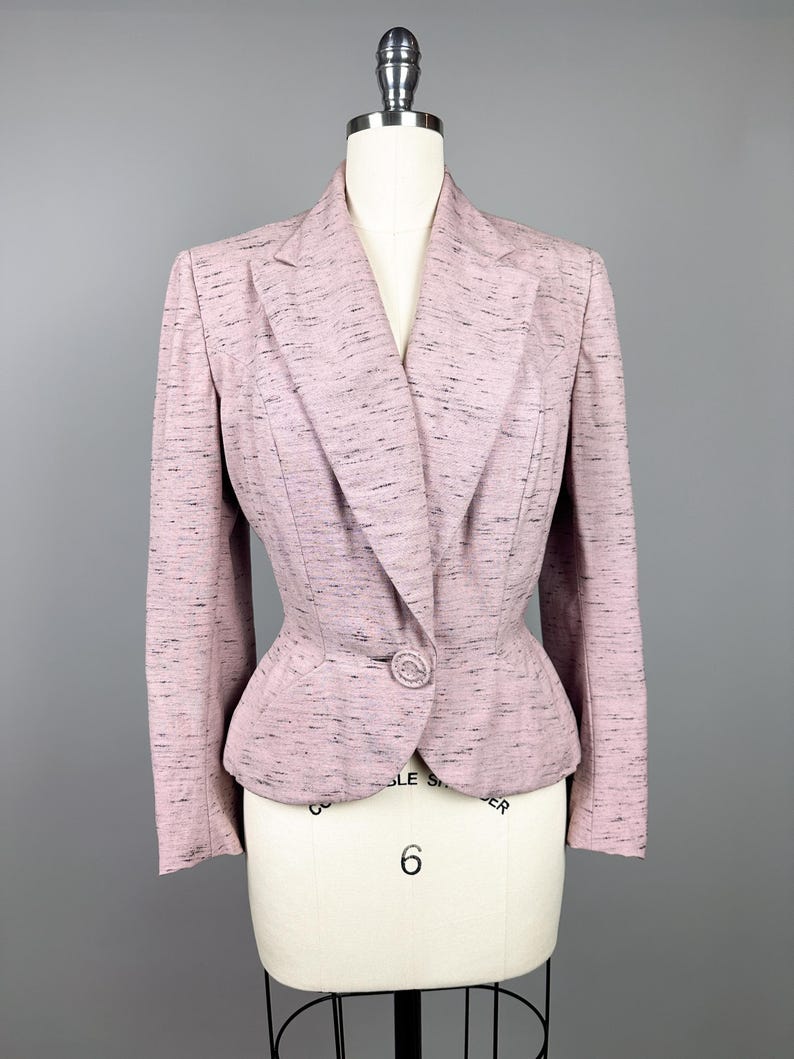 Puede incluir: Una chaqueta rosa con un patr&oacute;n moteado. La chaqueta tiene un cierre de un solo bot&oacute;n y una cintura ajustada.
