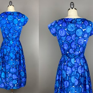 May include: A blue and white dress with a circle pattern. The dress has a scoop neck and short sleeves. It is fitted at the waist and has a full skirt.