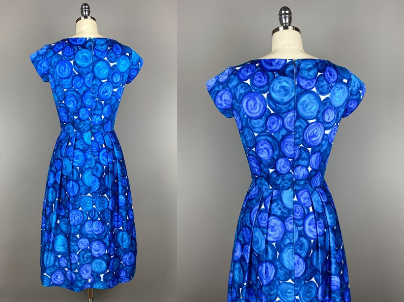 May include: A blue and white dress with a circle pattern. The dress has a scoop neck and short sleeves. It is fitted at the waist and has a full skirt.