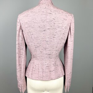 Puede incluir: Una chaqueta rosa con cintura ajustada y mangas largas. La chaqueta est&aacute; hecha de una tela texturizada con un brillo sutil.
