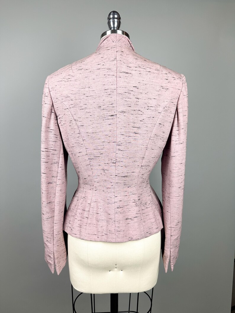 Puede incluir: Una chaqueta rosa con cintura ajustada y mangas largas. La chaqueta est&aacute; hecha de una tela texturizada con un brillo sutil.