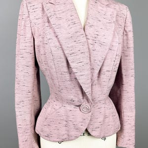 Puede incluir: Una chaqueta rosa con un cierre de bot&oacute;n &uacute;nico y una silueta ligeramente ajustada. La chaqueta tiene un patr&oacute;n moteado en toda su superficie.