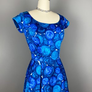May include: A blue and white vintage dress with a circle pattern. The dress has a scoop neck and short sleeves.