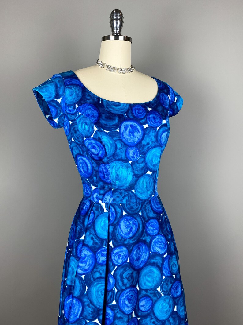 May include: A blue and white vintage dress with a circle pattern. The dress has a scoop neck and short sleeves.
