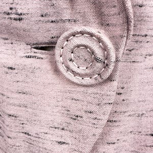 Puede incluir: Primer plano de una tela rosa con un patr&oacute;n moteado en blanco y negro. Un bot&oacute;n grande y redondo est&aacute; cosido en la tela.