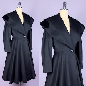 May include: A black vintage coat with a wide collar and a flared skirt. The coat features a single button closure at the waist and velvet accents on the shoulders. The coat is displayed on a mannequin.
