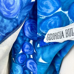 May include: A blue and white patterned fabric with a white tag that reads "GEORGIA BULLOCK" in black text.