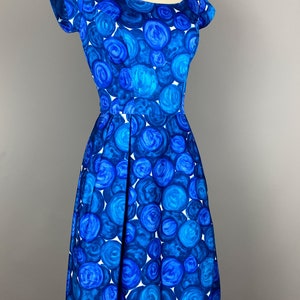 May include: A blue and white vintage dress with a circle pattern. The dress has a scoop neck and short sleeves.