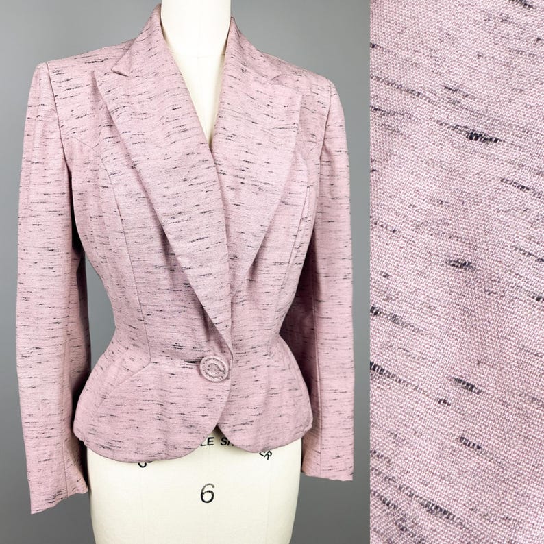 Puede incluir: Una chaqueta rosa con un cierre de bot&oacute;n &uacute;nico y una cintura ajustada. La chaqueta est&aacute; hecha de una tela texturizada con un brillo sutil.