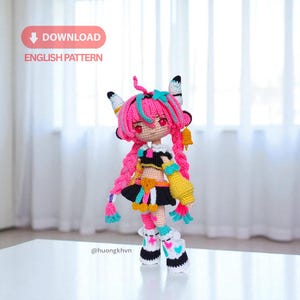 Pode incluir: Boneca de crochê feita à mão com cabelo rosa, detalhes azuis e uma roupa preta e amarela. A boneca tem um design detalhado, incluindo botas com padrões de coração. A imagem inclui o texto "DOWNLOAD ENGLISH PATTERN".