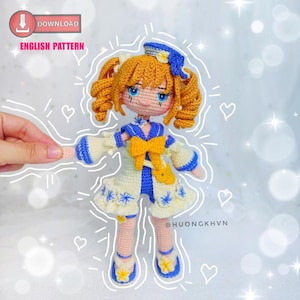 May include: Crocheted amigurumi doll with yellow hair, blue and white dress, and a yellow bow. The doll is wearing a blue and white sailor hat with a white flower on top. The doll is standing on a white background with hearts and stars.