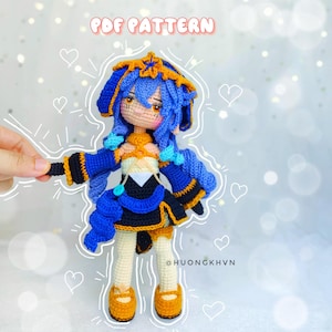 Può includere: Bambola amigurumi all'uncinetto con capelli blu, una corona gialla e un vestito blu e nero. La bambola è in piedi su uno sfondo bianco con cuori e linee disegnate intorno a lei. Il testo "PDF PATTERN" è nella parte superiore dell'immagine e "@HUONGKHVN" nella parte inferiore.