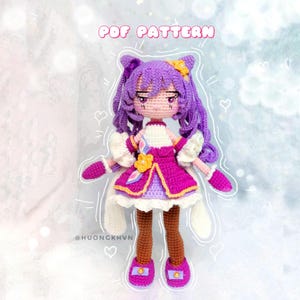 Puede incluir: Patrón de amigurumi de crochet para una muñeca de pelo morado que lleva un vestido rosa y blanco con flores amarillas. El patrón está disponible para descargar en PDF. La muñeca sostiene una varita blanca con una flor amarilla en la parte superior. La muñeca está de pie sobre un fondo blanco con un cielo azul claro en el fondo. El texto "PDF PATTERN" está escrito en letras negras sobre un fondo blanco.