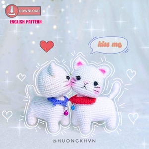 Puede incluir: Dos peluches de gato blancos de crochet besándose. El gato de la izquierda lleva un collar azul con una campanilla. El gato de la derecha lleva una bufanda roja. El texto "kiss me" está en un bocadillo de diálogo sobre los gatos.