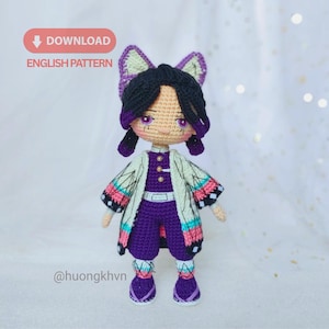 Könnte beinhalten: Handgefertigte Häkelpuppe in einem lila-weißen Outfit mit gemustertem Mantel. Die Puppe hat schwarzes Haar, lila Augen und ein Schmetterlings-Haaraccessoire. Der Text "DOWNLOAD ENGLISH PATTERN" ist enthalten.