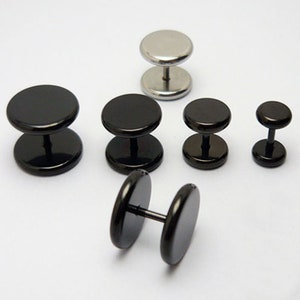 Könnte beinhalten: Ein Set aus sechs schwarzen und silbernen Edelstahl-Ohrsteckern. Die Ohrstecker sind in verschiedenen Größen und haben ein flaches, kreisförmiges Design.