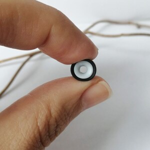 May include: A black and white plastic ring with a white center and a black outer ring.