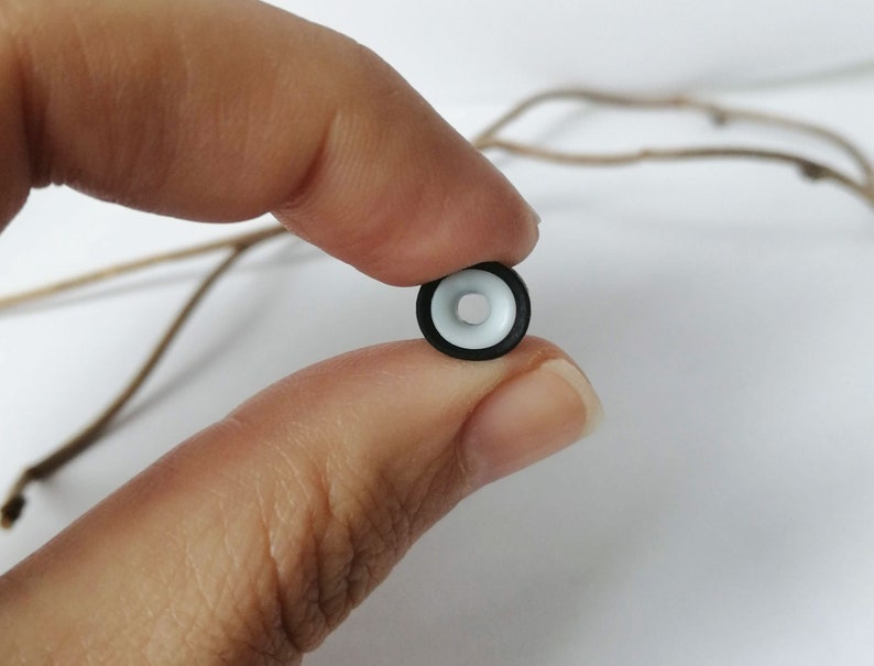 May include: A black and white plastic ring with a white center and a black outer ring.
