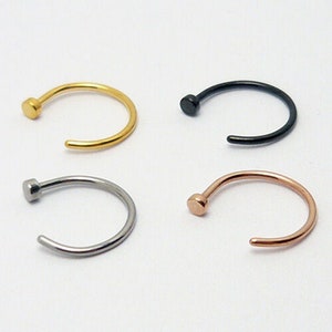 Könnte beinhalten: Vier Nasenringe in verschiedenen Farben: Gold, Silber, Schwarz und Roségold. Jeder Ring ist ein einfacher Kreis mit einer kleinen Kugel am Ende.