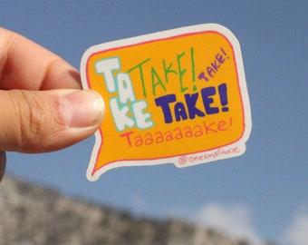 May include: A yellow sticker with a speech bubble shape and the text "TAKE! TAKE! TAKE! Taaaaaaaake!" in colourful lettering. The sticker is held in a hand against a blue sky background.