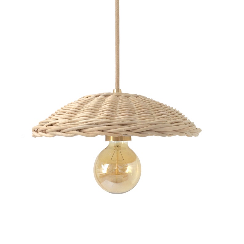 K&ouml;nnte beinhalten: Eine geflochtene H&auml;ngeleuchte aus Weide in nat&uuml;rlicher beige Farbe mit einem runden, leicht gew&ouml;lbten Schirm. Die Leuchte hat eine einzelne Gl&uuml;hbirne mit einem warmen, goldenen Schein.