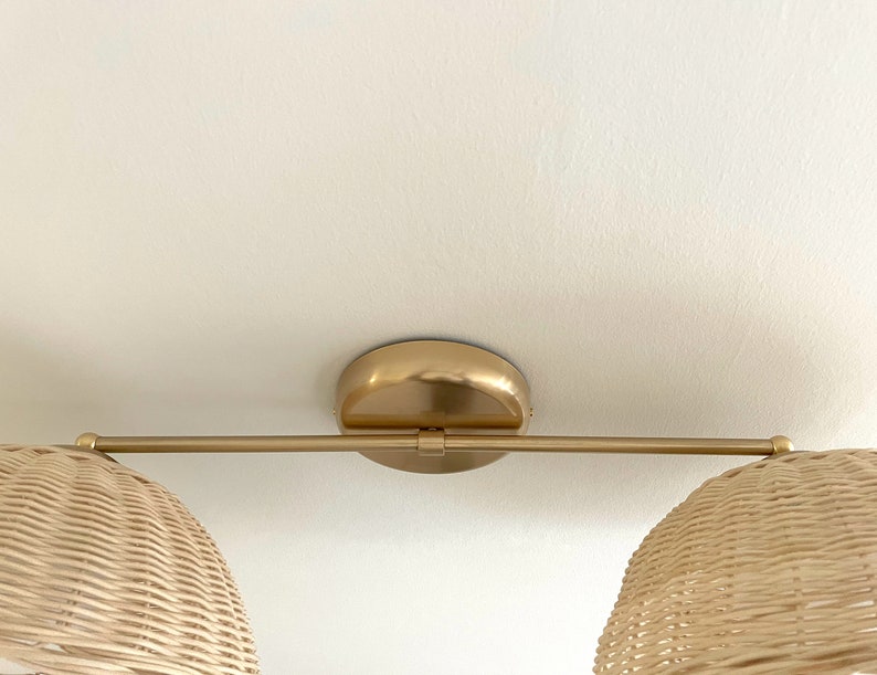 May include: A gold ceiling light fixture with two woven wicker shades. The fixture has a single arm that extends from the center.