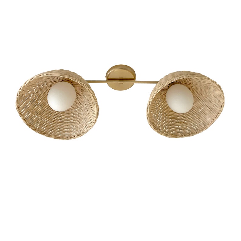 May include: A gold metal light fixture with two woven wicker shades and white globe light bulbs.