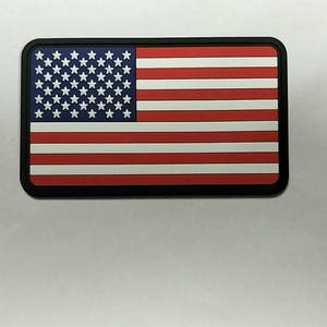 May include: A black and white American flag patch with red stripes. The patch is made of a durable material and is perfect for adding a patriotic touch to any item.
