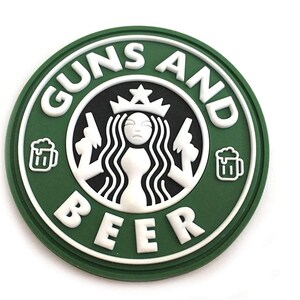 Puede incluir: Un parche redondo verde con texto blanco que dice "Guns and Beer" y una imagen en blanco y negro de una mujer con una corona sosteniendo dos armas. La mujer está rodeada de un círculo con una estrella en la parte superior.
