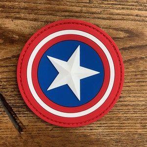 May include: A red, white, and blue embroidered patch with a white star in the center. The patch is circular and has a stitched edge.