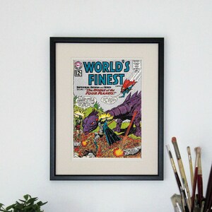 May include: A framed comic book cover featuring Superman, Batman, and Robin. The cover is titled "World's Finest" and features the text "The Riddle of the Four Planets".