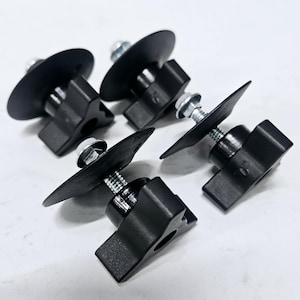 May include: Four black plastic and metal fasteners with a round base and a wing nut. The fasteners are used to secure items to a surface.