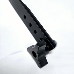 Puede incluir: Una abrazadera de metal negro con una perilla de pl&aacute;stico negro. La abrazadera tiene cuatro agujeros para sujetarla a una superficie.