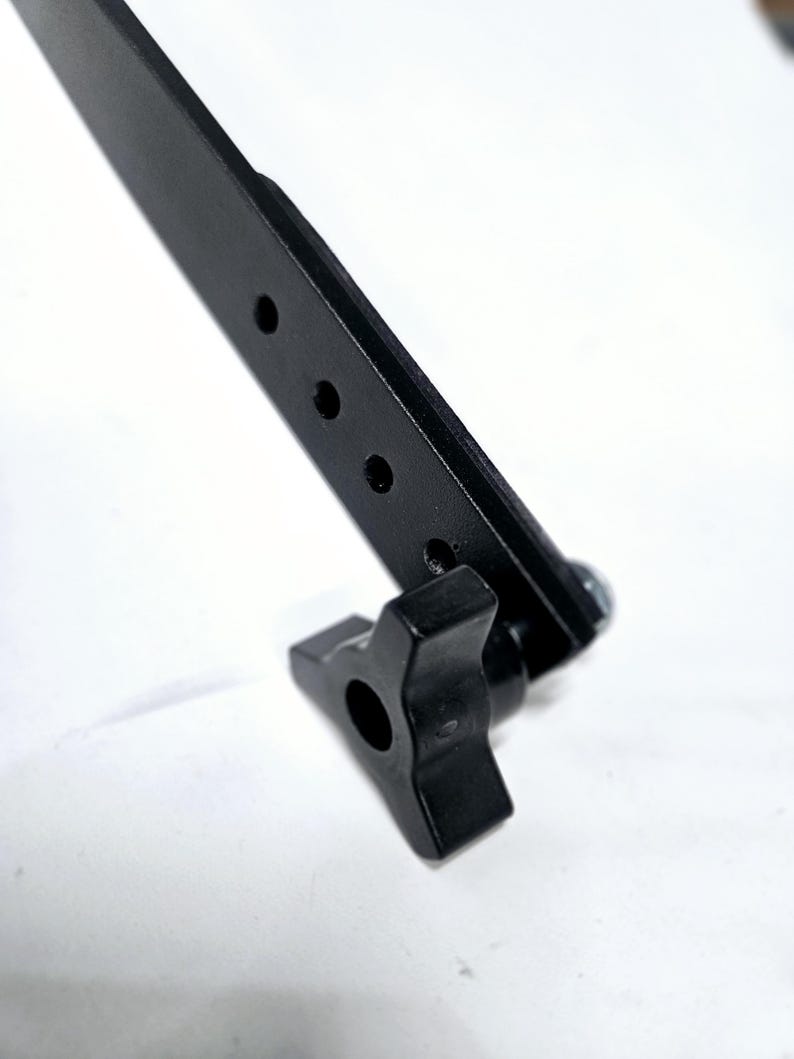 Puede incluir: Una abrazadera de metal negro con una perilla de pl&aacute;stico negro. La abrazadera tiene cuatro agujeros para sujetarla a una superficie.