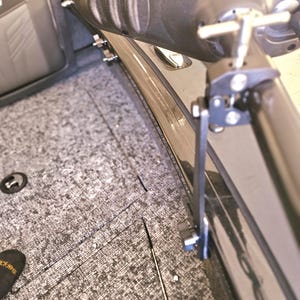 Puede incluir: Primer plano de un soporte de asiento de barco de metal negro con una manija en T plateada. El soporte est&aacute; unido a un asiento de barco gris.