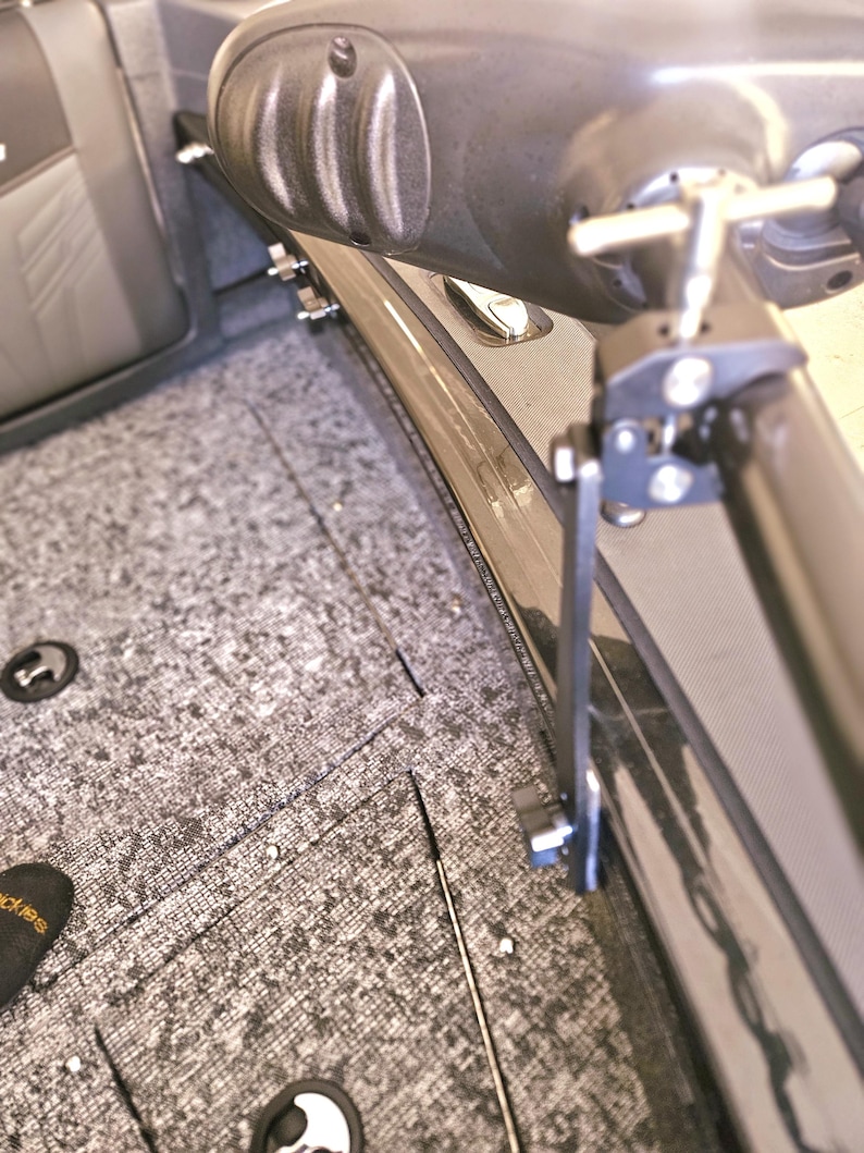 Puede incluir: Primer plano de un soporte de asiento de barco de metal negro con una manija en T plateada. El soporte est&aacute; unido a un asiento de barco gris.