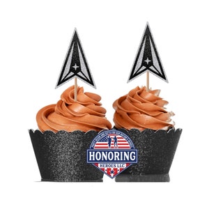 May include: Two chocolate cupcakes with black and silver glitter cupcake liners. Each cupcake has a silver glitter star with a black outline and a white star in the center. The cupcakes are topped with brown frosting. The cupcake liners have the text "HONORING HEROES LLC" in red, white, and blue.