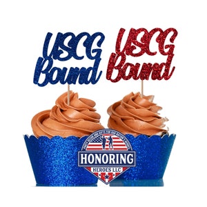 May include: Two chocolate cupcakes with blue glitter cupcake liners. The cupcakes are topped with red and blue glitter cupcake toppers that say "USCG Bound". The cupcake liners have a blue and white logo that says "Honoring Heroes LLC".