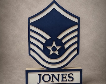 May include: A layered wooden sign featuring the United States Air Force Master Sergeant rank insignia in navy blue and white. The shield-shaped emblem includes a central star and chevron stripes, mounted on a rectangular base with the name JONES.