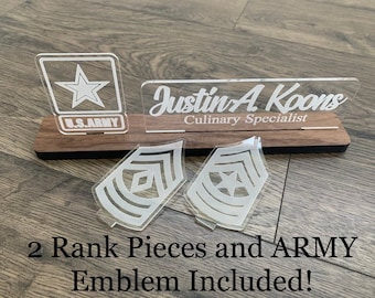 May include: A wooden plaque with a clear acrylic nameplate that reads "Justin A. Koons Culinary Specialist".  There are two clear acrylic rank insignia and a clear acrylic US Army emblem.