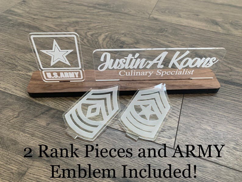 May include: A wooden plaque with a clear acrylic nameplate that reads "Justin A. Koons Culinary Specialist".  There are two clear acrylic rank insignia and a clear acrylic US Army emblem.