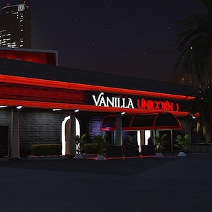 Puede incluir: Toma exterior nocturna de un edificio con luces de neón rojas. El letrero dice "Vanilla Unicorn" en letras blancas. Un logotipo de neón rojo está a la izquierda. El edificio tiene una fachada de ladrillo oscuro.