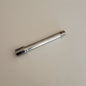 Könnte beinhalten: Eine silberne Stecknussverlängerung mit einem 1/2 Zoll Antrieb und einer 6-Kant-Stecknuss an einem Ende.