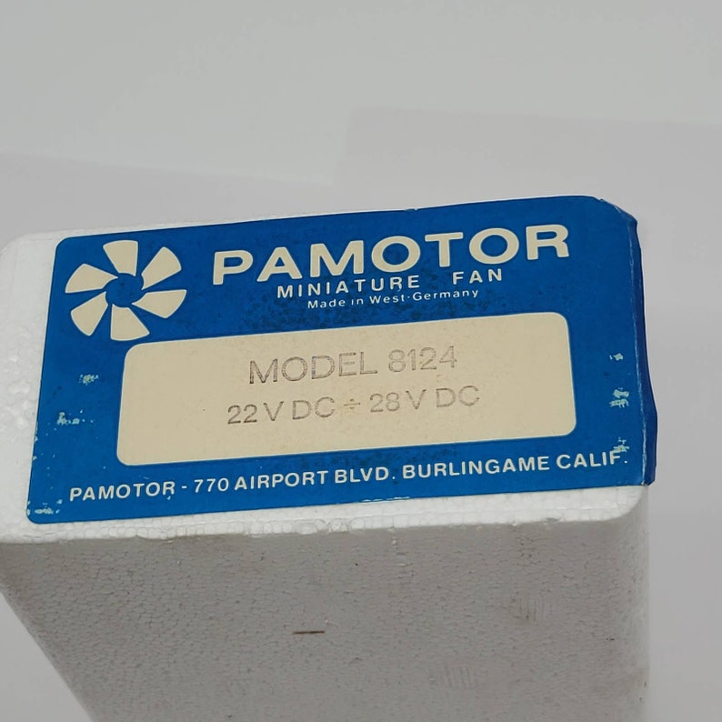 May include: A blue and white label from a PAMOTOR miniature fan. The label includes the text "MODEL 8124" and "22 V DC &divide; 28 V DC". The label also states "Made in West-Germany".