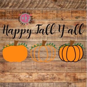 May include: Happy Fall Y'all text with three orange pumpkins with green vines on a wood background.