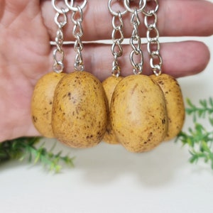 Puede incluir: Cuatro llaveros marrones con forma de patata con anillos y cadenas plateados.